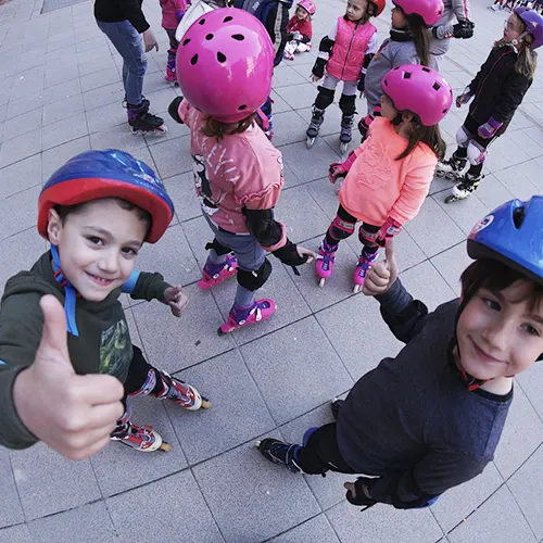 Patines para Niños - Niños con patines y casco saludando a cámara