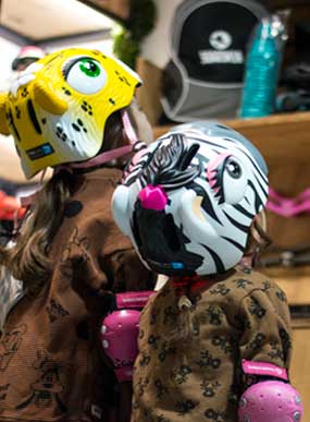 Comprar patines para niños - Dos niñas con cascos de animales mirando productos de patinaje